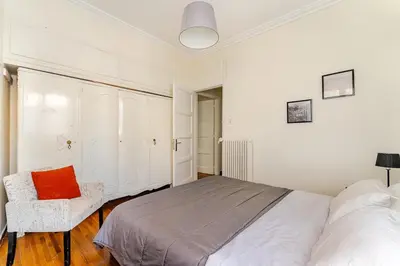 a white bedroom with a bed and a chair at 3BDR IDEAL CENTRAL ATHENIAN APT in Athens