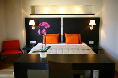 a bedroom with a bed with orange pillows and a red chair at O&B Athens Boutique Hotel in Athens