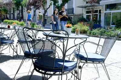 a table and chairs with people standing in the background at Phidias Hotel by Oniro in Athens