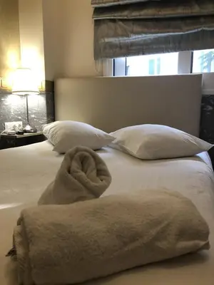 a bed with white pillows and a towel on it at Phidias Hotel by Oniro in Athens