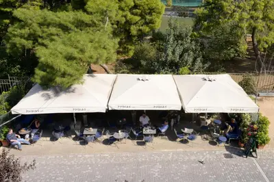 an overhead view of a restaurant with tables and white umbrellas at Phidias Hotel by Oniro in Athens