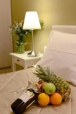 a tray of fruit on a bed with a bottle of wine at Phidias Hotel by Oniro in Athens