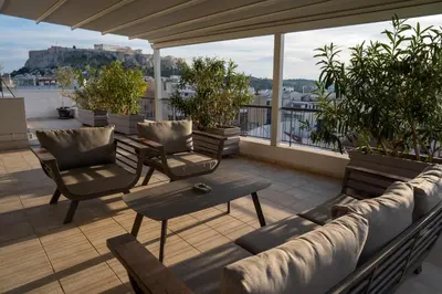 a patio with a couch and chairs on a balcony at V&V Acropolis view apartment in Athens