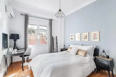 a white bedroom with a bed and a desk and a window at Retropolitan Living Athens in Athens
