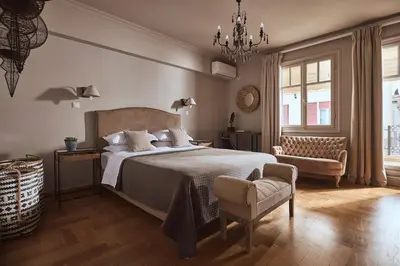 a bedroom with a bed and a chair and a chandelier at Plaka's Villa with Breathtaking Acropolis view in Athens