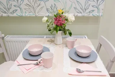 a table with two cups and a vase with flowers at Grandma's Chic & Bright Athenian home with a Patio in Athens