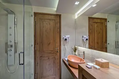 a bathroom with a sink and a shower with a wooden door at Estia Boutique Apartments in Athens