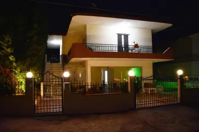 a white house with a balcony at night at Galotel Agnoudas near the airport in Markopoulo