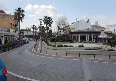 a cobblestone street in a town with palm trees and buildings at Galotel Agnoudas near the airport in Markopoulo