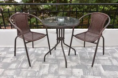 a glass table and two chairs on a patio at Galotel Agnoudas near the airport in Markopoulo