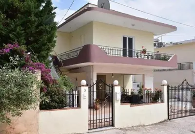 a large white house with a black gate at Galotel Agnoudas near the airport in Markopoulo
