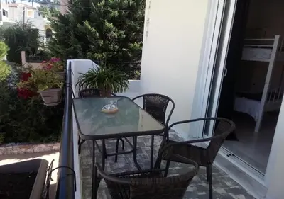 a glass table and chairs on a balcony at Galotel Agnoudas near the airport in Markopoulo