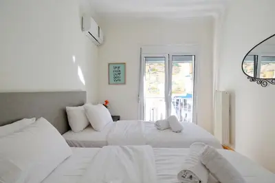 two white beds in a white room with a window at Athens Heartbeat in Athens