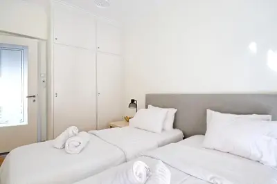 two beds in a room with white sheets and towels at Athens Heartbeat in Athens