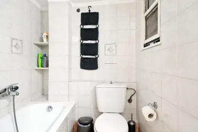 a white bathroom with a toilet and a bath tub at Athens Heartbeat in Athens