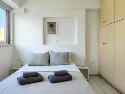 a white bed with two purple pillows on it at KYMA Apartments - Athens Acropolis 14 in Athens