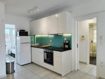 a kitchen with white cabinets and a green wall at KYMA Apartments - Athens Acropolis 14 in Athens