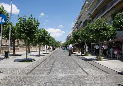 a cobblestone street with trees and people walking down it at Attractive Flat near the Acropolis Museum & Metro Station by Athenian Homes in Athens