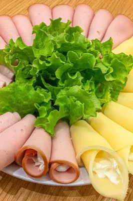a plate of food with sausage and lettuce and cheese at Hotel @Syngrou Fix in Athens