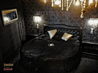 a bedroom with a bed with a black blanket and pillows at Carol Hotel in Piraeus