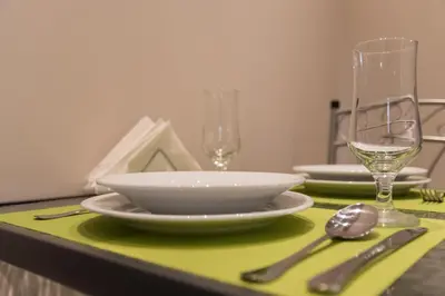 a table with a green table cloth with plates and wine glasses at Quality Home in Athens in Athens