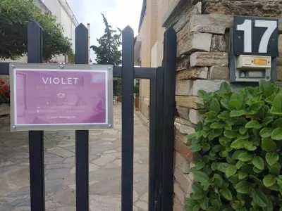 a sign on two poles in front of a building at Violet Bedroom and Apartment in Spáta