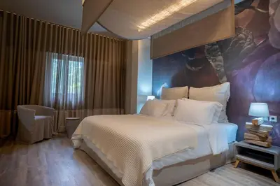 a bedroom with a bed and a painting on the wall at Mikelina Boutique Hotel in Pallíni