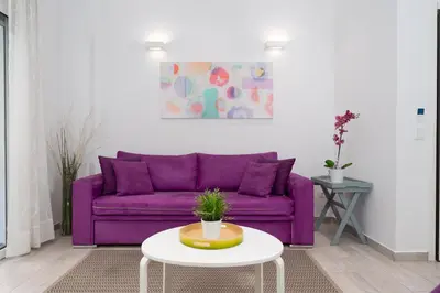 a purple couch in a living room with a table at Spacious Modern Apartment in Athens near Metro in Athens
