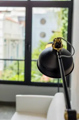 a black lamp sitting on a couch in front of a window at Soho Apartments in Athens