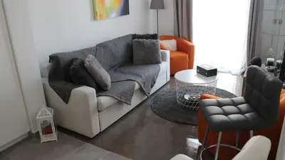 a living room with a white couch and an orange chair at Adrianou 150 in Athens