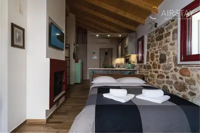 two beds in a room with a stone wall at Orianna Apartment Airport by Airstay in Spáta