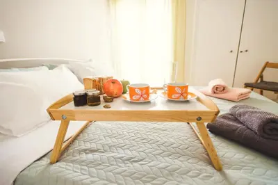 a coffee table with cups and food on a bed at Fotini's place! in Athens