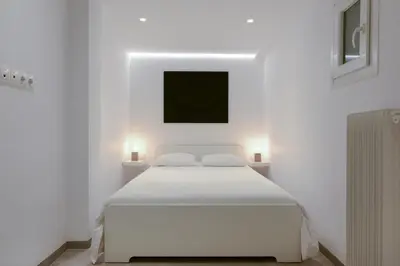 a white bedroom with a white bed and two lights at Athens One Apartment by Olala Homes in Athens