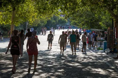 a group of people walking down a sidewalk in a park at Your home @Acropolis Museum in Athens