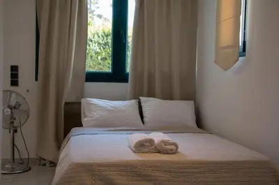 a bed with two towels on it with a window at Summer Villa Lagonissi in Lagonissi