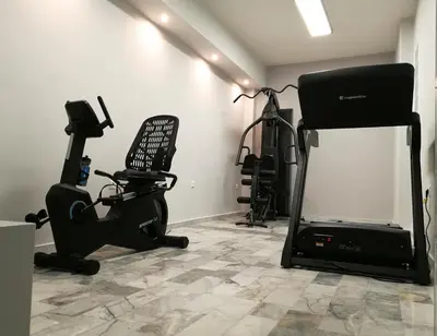 a room with a gym with a chair and a treadmill at Erato Hotel in Agia Marina Aegina