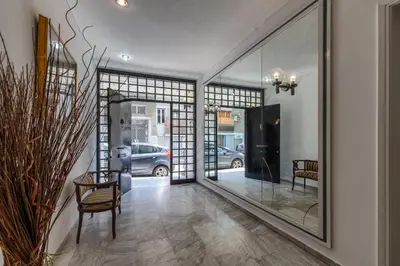 a hallway with glass doors and a chair and a mirror at Acropolis Koukaki Loft Private Garden in Athens