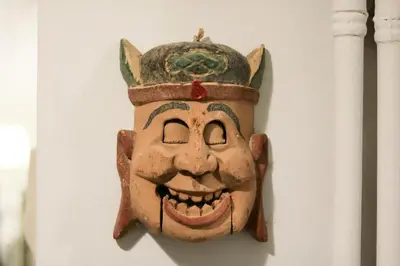 a mask hanging on a wall with a smile at Victoria Jewels in Athens
