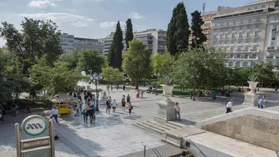a group of people walking around a plaza in a city at Ermou Stylish Suites by GHH in Athens
