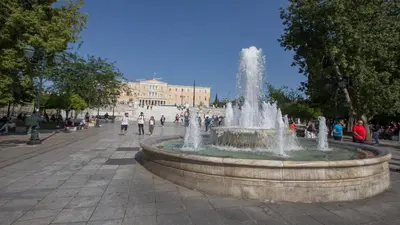 a fountain in a plaza with people walking around it at Ermou Stylish Suites by GHH in Athens