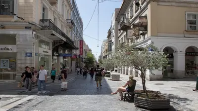 a group of people walking down a street with buildings at Ermou Stylish Suites by GHH in Athens