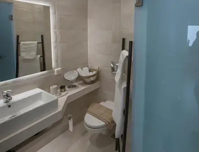a bathroom with a sink and a toilet and a mirror at Ermou Stylish Suites by GHH in Athens