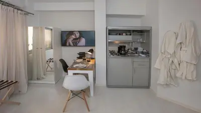 a white kitchen with a table and a white chair at Ermou Stylish Suites by GHH in Athens