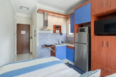 a small kitchen with blue cabinets and a refrigerator at Island in the sky! Acropolis and city views! in Athens