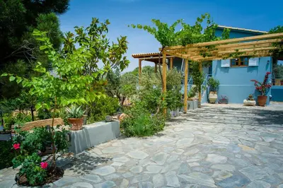 a garden with a stone patio and a pergola at Marianna Cottage in Palaiá Fókaia