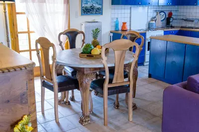a kitchen with a wooden table with chairs and fruit on it at Marianna Cottage in Palaiá Fókaia