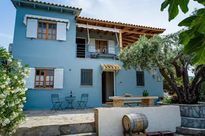 a blue house with a table and chairs at Marianna Cottage in Palaiá Fókaia
