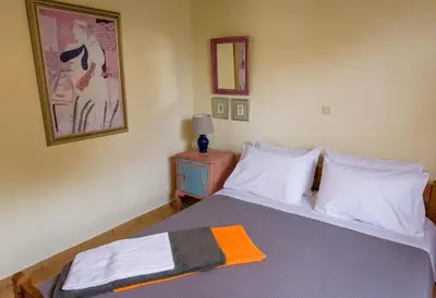 a bedroom with a bed with an orange blanket on it at Marianna Cottage in Palaiá Fókaia