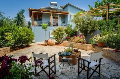 a patio with a table and chairs in front of a house at Marianna Cottage in Palaiá Fókaia