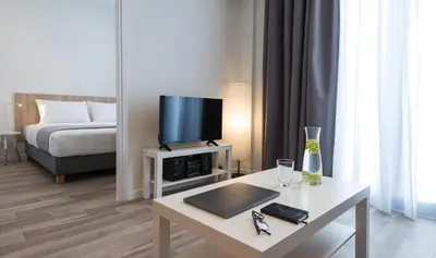 a living room with a table with a laptop and a tv at Spot Apart in Athens